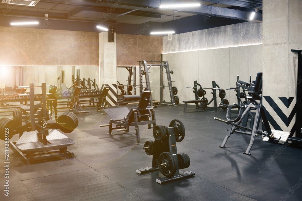 Fototapeta premium Weight plate rack and exercise machines in sunlit gym