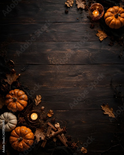 Festive halloween background with pumpkins and autumn leaves on a rustic dark wooden table with copy space