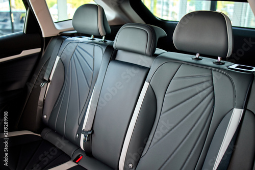 Foto Rear leather car seats with center armrest, three headrests, visible seatbelt bu