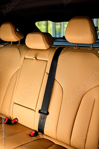 Obraz na plátně Rear leather car seats with center armrest, three headrests, visible seatbelt bu