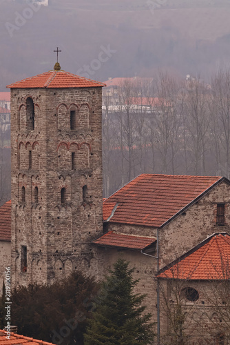 Stone church in Cortemilia, in the Province of Cuneo. Spring view with overcast skies and light haze highlighting historic Italian architecture, stone masonry and the quiet atmosphere of the countrysi