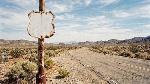 Abandoned Route 66 sign beside an empty desert road  
