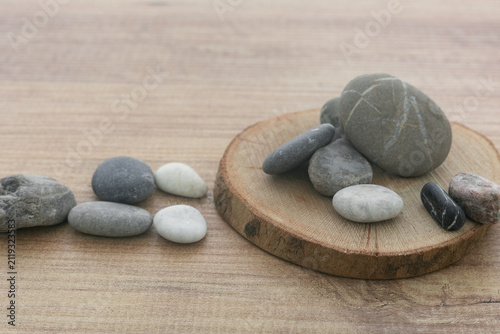 Photography Natural sea pebbles pile on round wooden slice background.