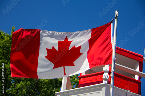 Canadian flag next to a lighthouse