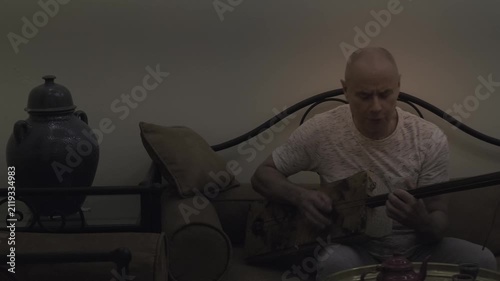 elderly man sings while playing handmade instrument in Traditional Moroccan riad, blending culture, passion, and musical heritage, authentic experience, exotic travel