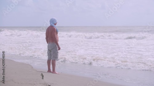 Senior man standing sea water, enjoying waves and fresh air, peaceful moment, walks barefoot in foamy surf relaxation, freedom and calmness, connection with nature stormy weather, healthy lifestyle,