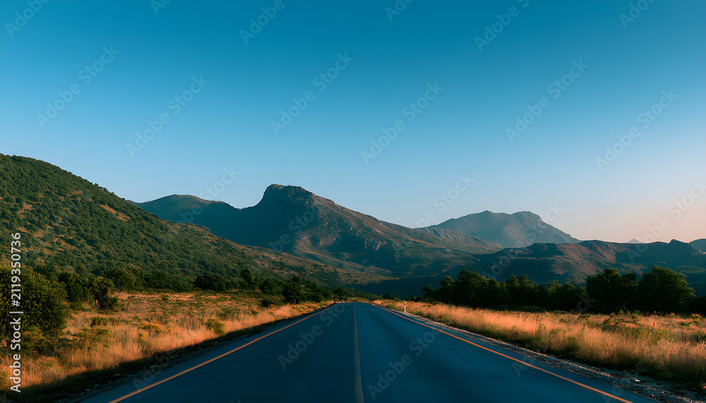 Obraz premium Empty asphalt road and green mountains under clear blue sky