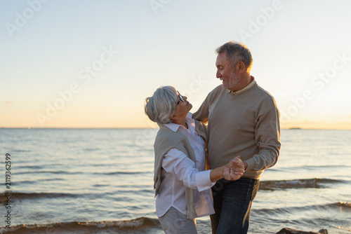 Keep moving. Romantic senior mature couple dancing together on beach outdoor recreation. Happy smiling family retired man woman husband wife having fun enjoying time together. Family moment love care