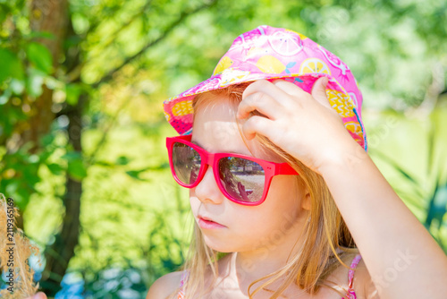 Happy little girl wearing pink fruit print bucket hat and sunglasses, sunny summer day outdoors, Sun protection, safety in hot weather, child fashion and style, children vacation travel lifestyle