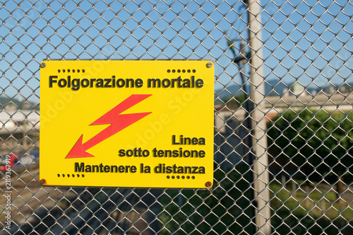 High voltage danger sign warning of fatal electrocution on railway fence in Chiasso