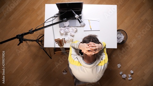 Photography Perplexed musician experiencing writer's block, sitting at a desk with a laptop,