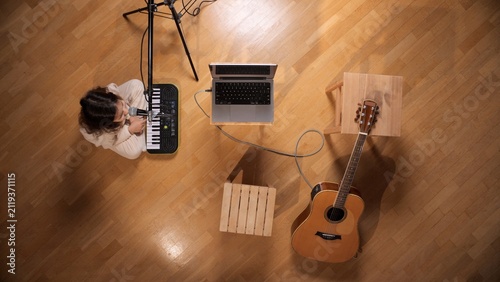 фотографія Young woman recording a song with a microphone and midi keyboard, connecting mus
