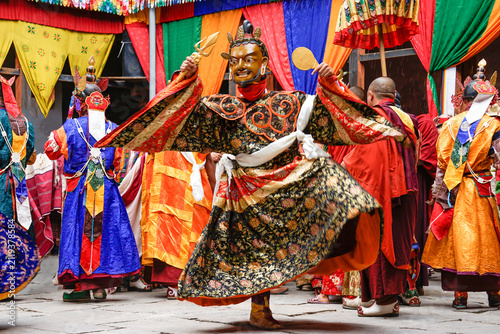 Bhutan, In the village of Bumthang, a monk in colorful costumes dances during the Jakar festival.
