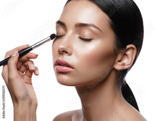 Close up portrait of a young woman getting eye makeup applied with brush