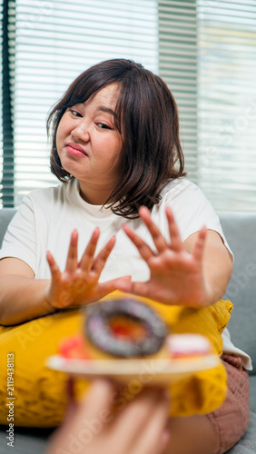 Overweight teenage girl rejecting sweets and choosing fruit for healthy eating, weight loss, obesity prevention, nutrition, and wellness concept.