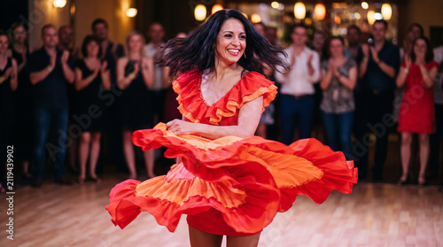 Fiery salsa dancer twirling dress on wooden floor with vibrant motion energy, cultural rhythm performance, festive celebration atmosphere, passion and symbolic movement