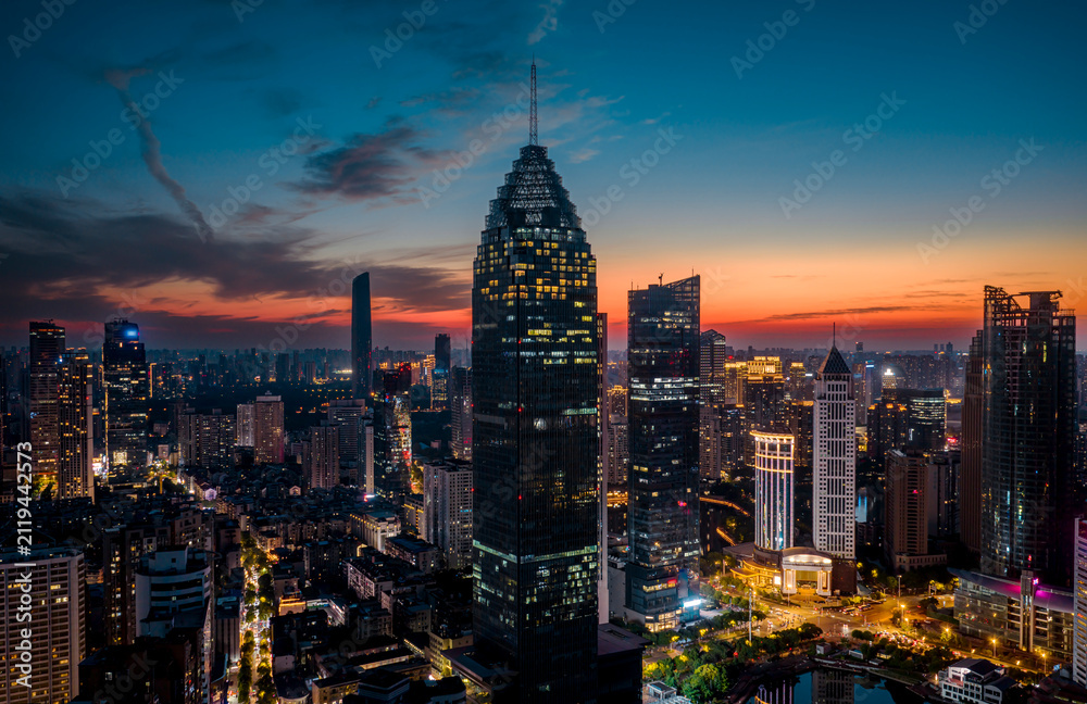 Fototapeta premium Aerial twilight view of Wuhan Financial Street CBD. The towering, illuminated skyscrapers reflecting in the water symbolize the dynamic growth of China's economy. 