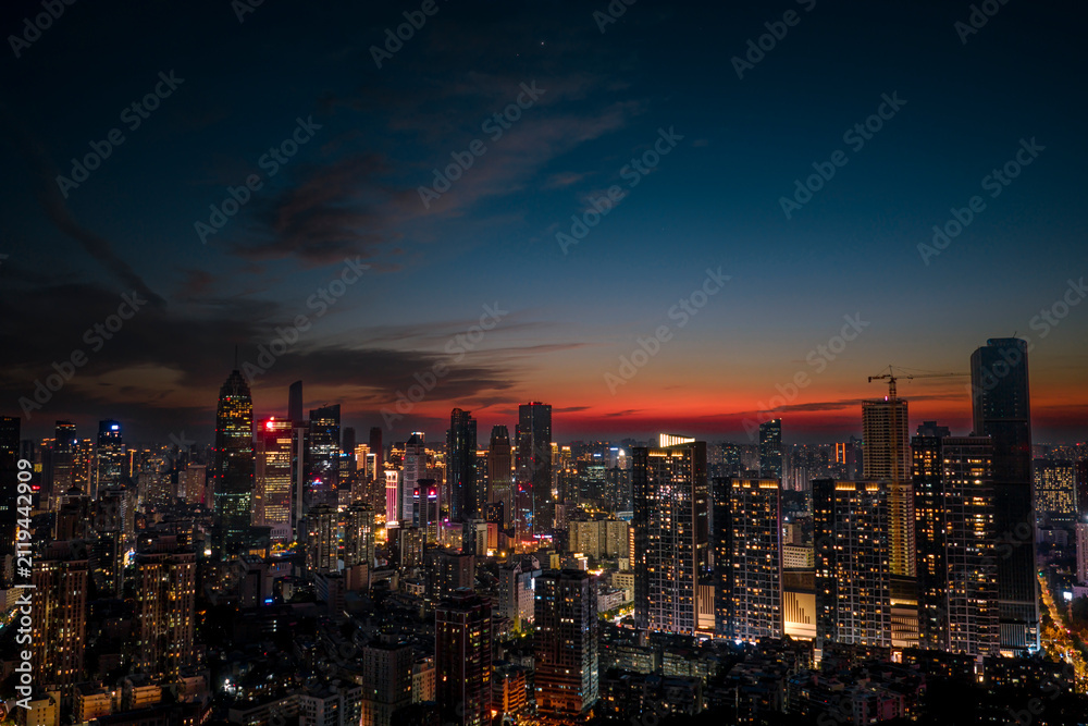 Fototapeta premium Aerial twilight view of Wuhan Financial Street CBD. The towering, illuminated skyscrapers reflecting in the water symbolize the dynamic growth of China's economy.