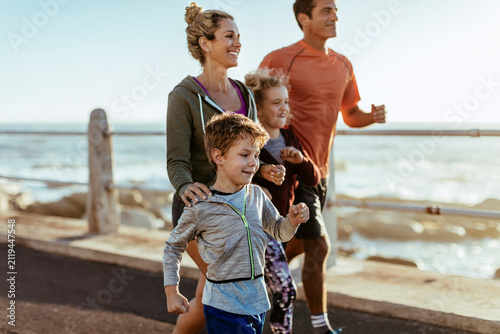 Smiling family jogging together on oceanfront boardwalk