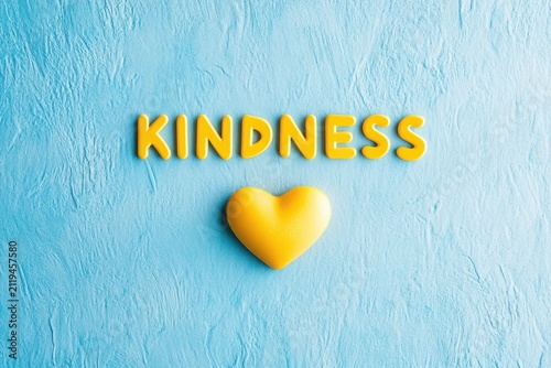 Yellow kindness word art with heart symbol promotes positive actions and compassionate global community awareness