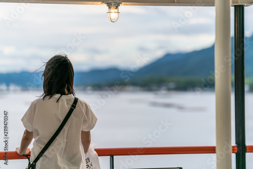 A lonely asian woman standing at side of a ship