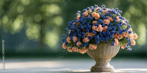 A vibrant bouquet of small blue and orange pink flowers in a classic stone urn