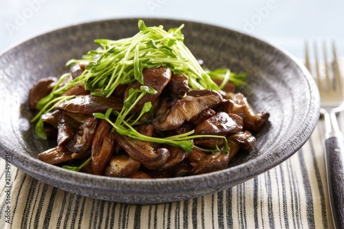 Sauteed fungi with herbs in a ceramic bowl on a striped placemat