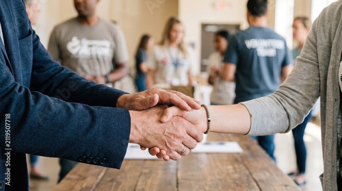 leadership development nonprofits volunteer concept. Two people shaking hands in a casual meeting setting with others in background