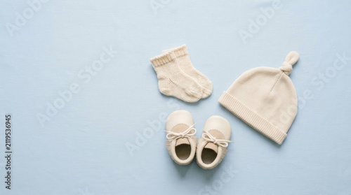Flat lay top view of newborn baby clothing items on a soft light blue background