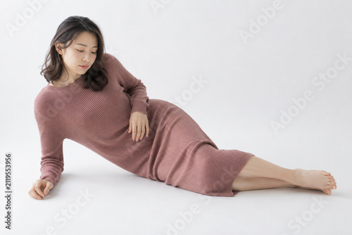Naklejka 白いスタジオで横たわるローズ色ニットドレスの女性