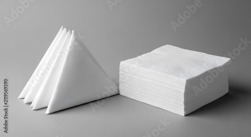 Stack of white paper napkins and folded triangular serviettes isolated