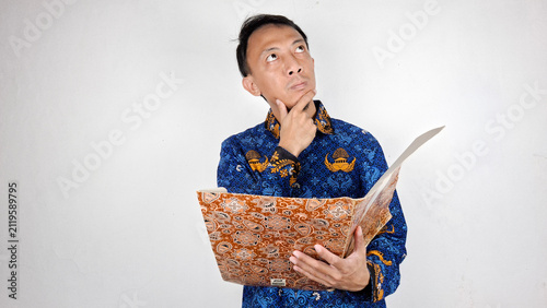 Foto Young male civil servant having a thought in blue batik uniform