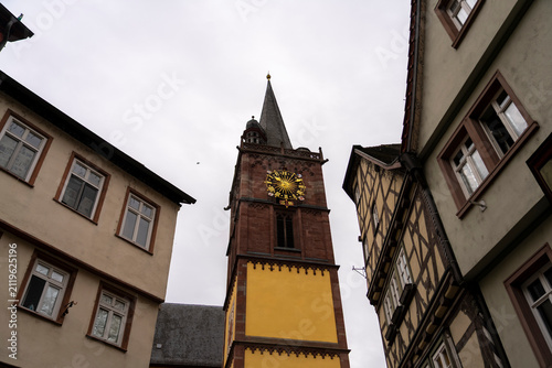 Church tower with clock between historic buildings
