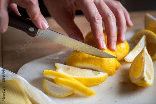 Cuadro en lienzo Hands slicing fresh lemons precisely