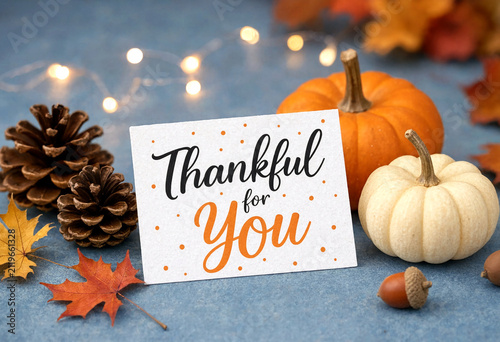 Thankful greeting card with autumn pumpkins pinecones and colorful leaves on table
