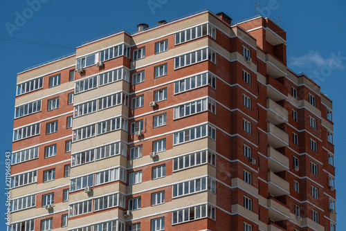 Photography Tall brick apartment building under a clear blue sky with many windows showing d
