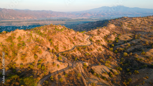 Foto Drone View of Coastal Mountain Road at Sunset in Sumbawa, Indonesia