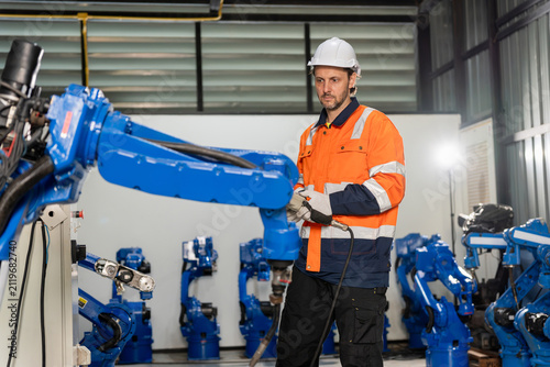 Fotografie Engineer operating robotic arm in manufacturing warehouse, Industrial technician