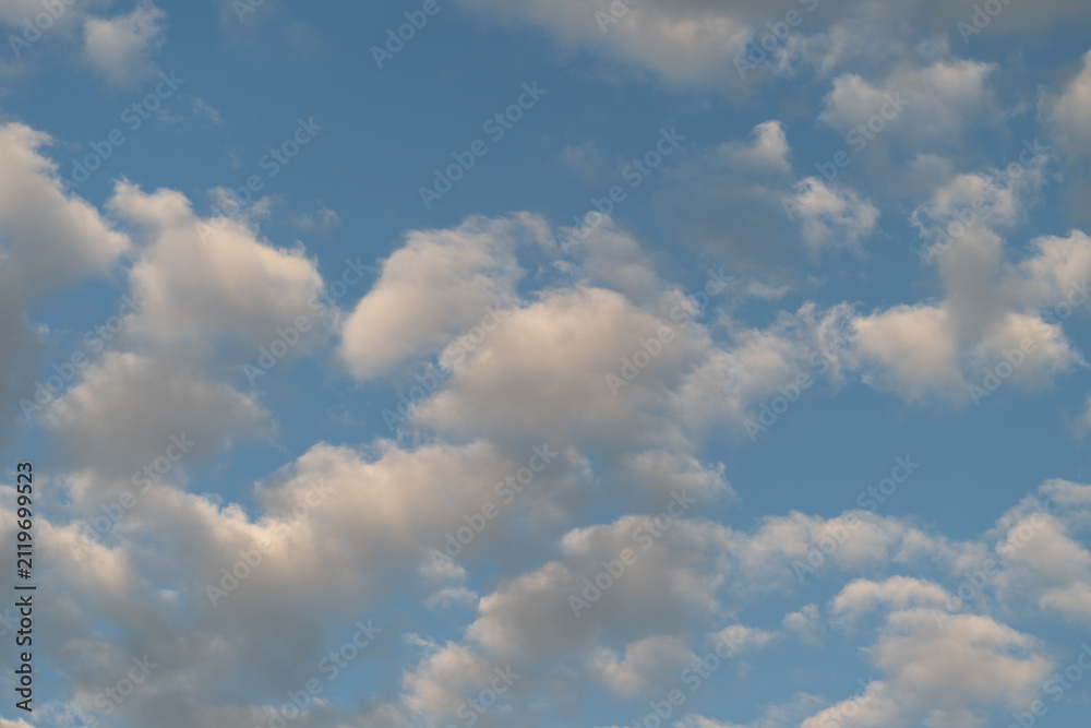 Fototapeta premium Scattered cumulus clouds across a blue sky at golden hour