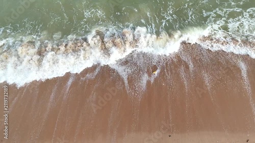 Aerial video shows waves crashing onto the sandy beach.