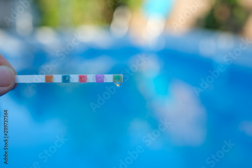 Close Up Testing Pool Water pH with Test Strip. Home Swimming Pool Water Quality Control. Shallow Depth of Field.