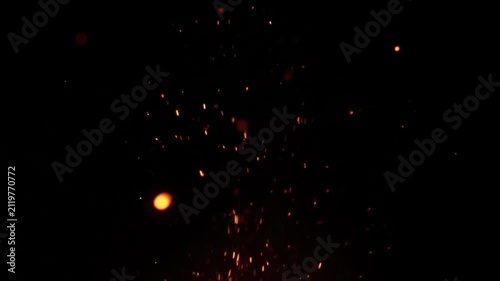 Bright orange glowing fire sparks flying and floating in the dark night air for background design