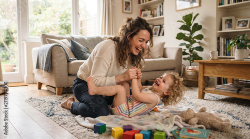 Happy Young Woman Playing with a Baby on Sofa at Home Enjoying Fun Relaxed Lifestyle Indoors