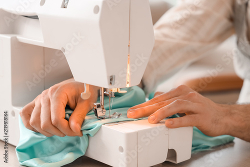 фотографія Young male tailor using sewing machine in atelier, closeup
