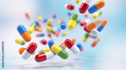 Colorful two-tone capsules falling and floating against a light blue background