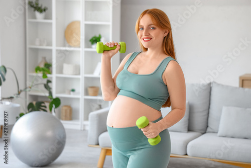 Sporty pregnant woman with dumbbells at home