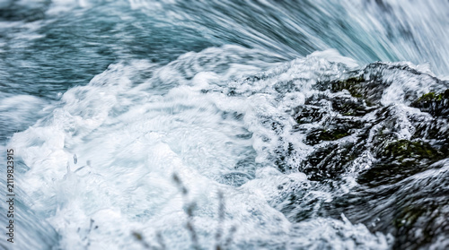 Waterfall streams crashing over dark rocks with white foam Generative AI