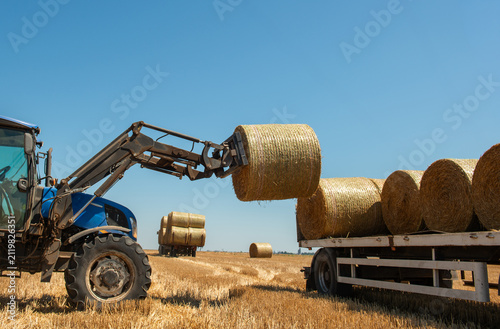  Tractor loading hay bales on truck trailer