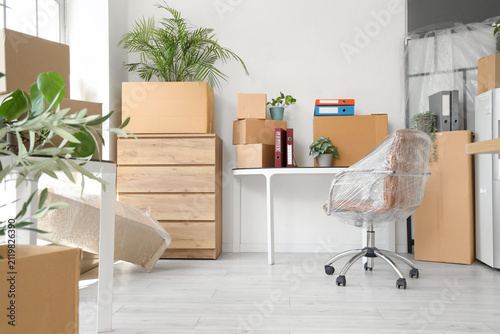 Workplace with plants, folders and boxes in office on moving day