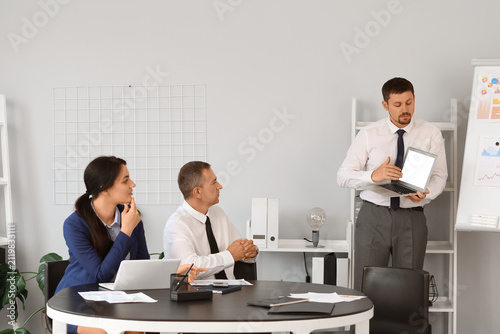 Male business consultant giving presentation to his colleagues in office